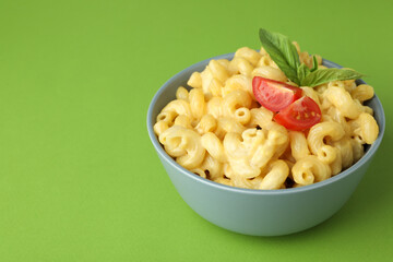 Plate with macaroni and cheese on green background