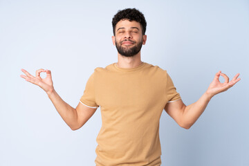 Young Moroccan man isolated on blue background in zen pose