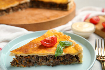 Piece of delicious pie with minced meat, tomato and basil served on table, closeup