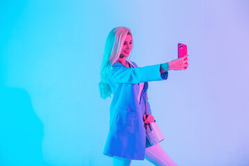 Cool happy young business woman in bright fashionable clothes with blazer takes selfie photo on...