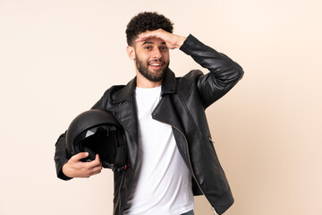 Young Moroccan man with a motorcycle helmet isolated on beige background doing surprise gesture while looking to the side