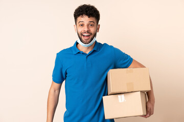 Young delivery Moroccan man isolated on beige background with surprise and shocked facial expression