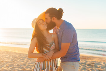 Young couple is spending time together outdoor, on a beach, at sunrise.