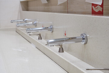 Row of modern white ceramic washbasin in public toilet or restaurant or hotel or shopping mall.