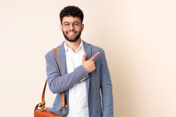 Young business Moroccan man isolated on beige background pointing to the side to present a product - obrazy, fototapety, plakaty