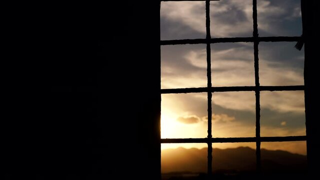 Time lapse of dark evening clouds moving on sky seen through iron barred window. Crime, prison cell bars.