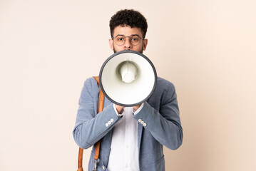 Young business Moroccan man isolated on beige background shouting through a megaphone