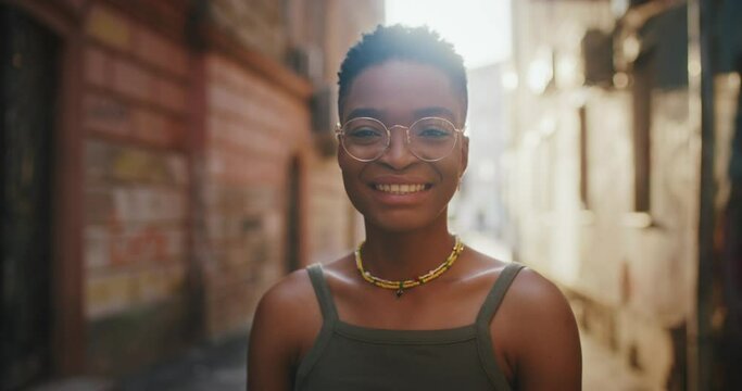 Portrait of gorgeous young stylish black woman wearing glasses. Cheerful African fashionable girl smiling of joy outside the street. Sunny beautiful day.