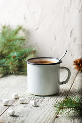 Hot coffee with marshmallow in a white mug with fir tree branch. Winter holiday Christmas drink