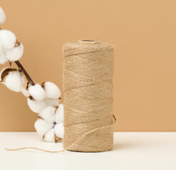 Fototapeta na wymiar reel with brown rope on a white table, packing material