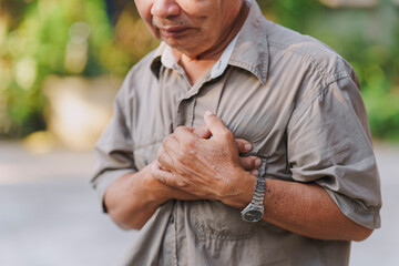 An old man holds his chest in pain. Concept of heart disease.