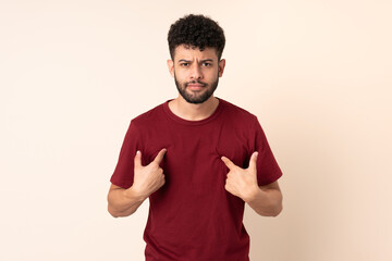 Young Moroccan man isolated on beige background pointing to oneself