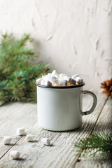 Hot coffee with marshmallow in a white mug with fir tree branch. Winter holiday Christmas drink