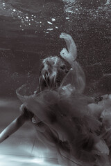 A girl with long hair swims underwater in a pink dress. She looks like an underwater dragon. Suitable for advertising