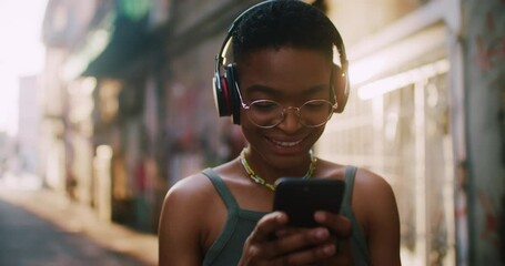 Beautiful woman in fashion outfit using mobile phone outside, typing messages, smiling and listening music. People , communication and joy. Street hipster. Stylish girl.