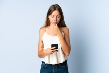 Young Lithuanian woman isolated on blue background thinking and sending a message