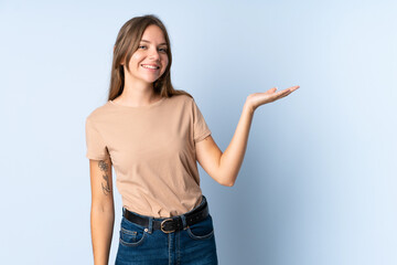 Young Lithuanian woman isolated on blue background holding copyspace imaginary on the palm to...