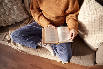 people, season and leisure concept - close up of woman in warm sweater reading book at home - obrazy, fototapety, plakaty
