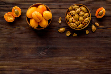 Ripe apricots in bowl with apricot kernel, top view