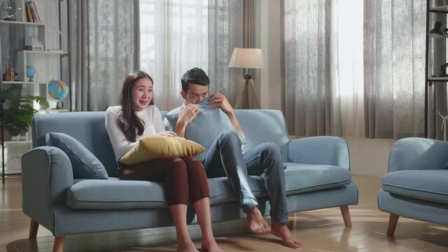 Young Asian Couple Watching Scary Movie On Tv At Home
