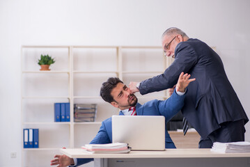 Old boss and young male employee in bullying concept