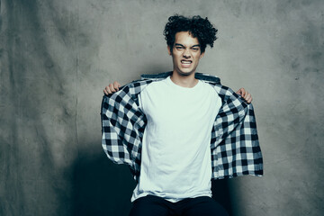 cute guy in a plaid shirt sitting on a chair posing studio