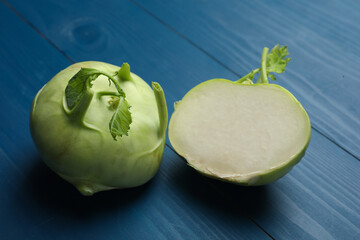 Whole and cut kohlrabi plants on blue wooden table