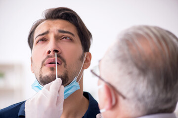 Young male patient visiting old male doctor during pandemic