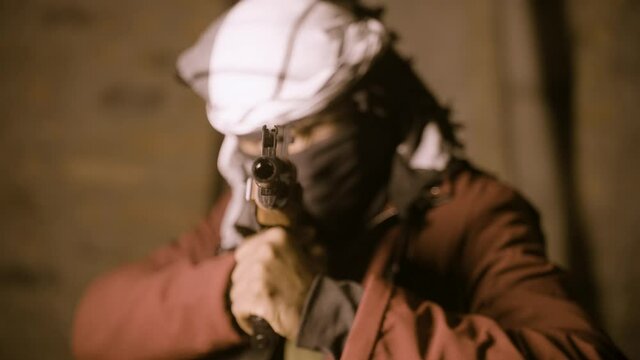 Selective focus on gun, terrorist or mafia gangster in face cover with gun looking or searching for target - concept of crime and warfare tactics.