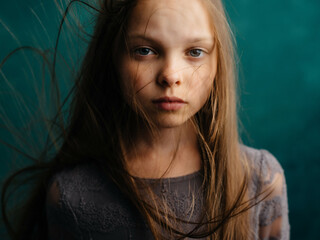 little girl loose hair close-up green background emotions depression