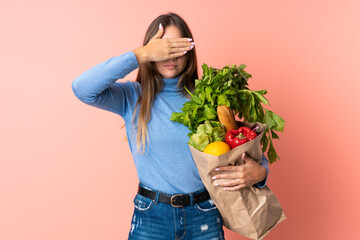 Young Lithuanian woman holding a grocery shopping bag covering eyes by hands. Do not want to see something