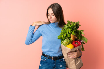 Young Lithuanian woman holding a grocery shopping bag suffering from pain in shoulder for having made an effort