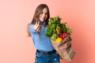 Young Lithuanian woman holding a grocery shopping bag making money gesture