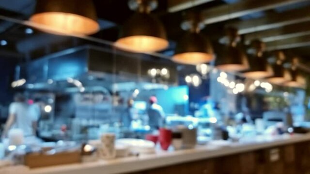 Blurred (bokeh) video of a large open kitchen in a modern restaurant. Great background for your food product presentation.