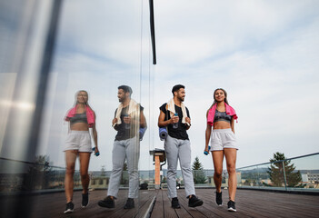 Young couple talking after exercise outdoors on terrace, sport and healthy lifestyle concept.