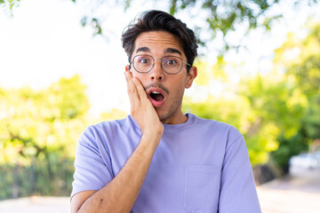 Young caucasian man at outdoors in a park surprised and shocked while looking right