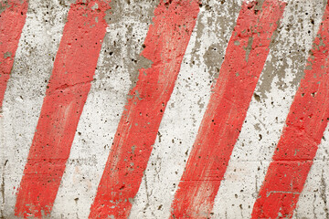 The texture of red and white stripes located diagonally on a concrete block of a city fence during road construction works.Signal marking, sign, stop of special equipment, Parking, dangerous area.