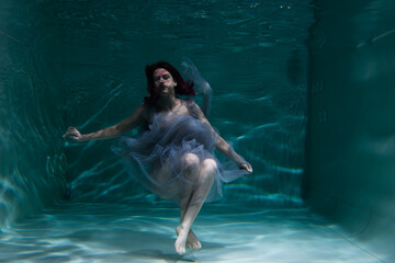 Photo of a beautiful girl with red hair posing in the water. She looks like a mermaid