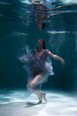 Photo of a beautiful girl with red hair posing in the water. She looks like a mermaid