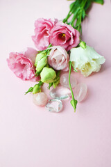Fototapeta na wymiar Beautiful pink eustoma (lisianthus) flowers in full bloom with rose quartz and rock crystal. Bouquet of flowers on pink background