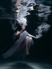 Photo of a beautiful girl with red hair posing in the water. She looks like a mermaid