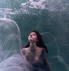 Photo of a beautiful girl with red hair posing in the water. She looks like a mermaid