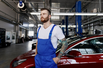 Strong minded young male professional technician car mechanic repairman man 20s in denim blue...