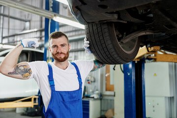 Cool strong repairman young professional technician mechanic man 20s wears denim blue overalls...