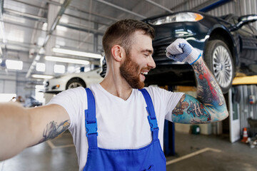 Close up young professional technician mechanic man in blue overalls t-shirt do selfie shot pov...