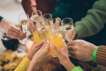 Cropped view portrait of big family eating domestic dish having fun clinking glasses orange juice at home indoors
