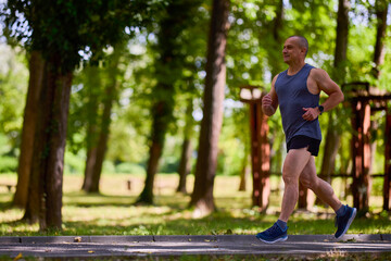 Man running in nature through the park, sports in the city.