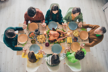 High angle photo of adorable cute family eating holiday turkey sitting table praying holding arms indoors house room