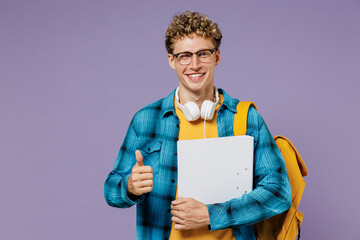 Young boy teen student in casual clothes backpack headphones glasses hold folder papers document show thumb up isolated on violet background studio Education in high school university college concept. © ViDi Studio