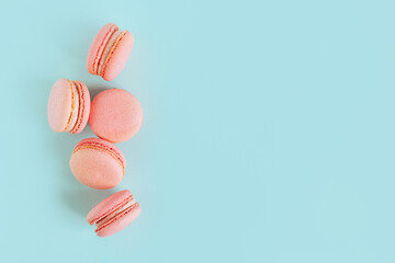 Obraz premium Tasty french pink macarons on a blue pastel background.